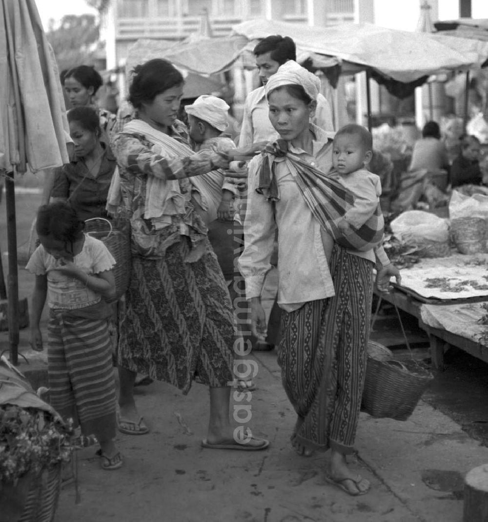 Vientiane: Frauen tragen ihre Babys in Tragetüchern über den Markt in Vientiane, der Hauptstadt der Demokratischen Volksrepublik Laos.