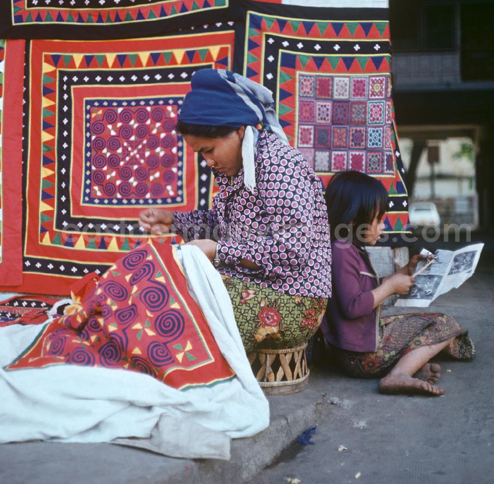 GDR image archive: Vientiane - Eine Frau aus dem Volksstamm der Meo, auch Hmong genannt, verkauft selbstgenähte Decken in Vientiane, der Hauptstadt der Demokratischen Volksrepublik Laos. Die Hmong gehörten zu einer infolge des Vietnam-Krieges verfolgten und zurückgezogen lebenden Minderheit in Laos.