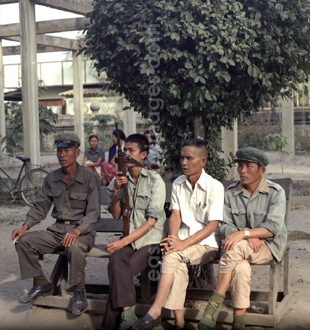 GDR image archive: Vientiane - Milizionäre sitzen auf einer Bank in Vientiane in der Demokratischen Volksrepublik Laos.