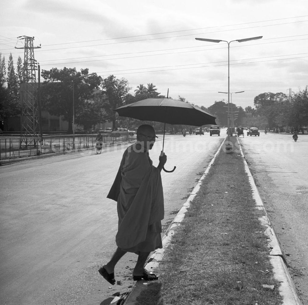 GDR photo archive: Vientiane - Ein Mönch mit Schirm läuft über eine Straße in Vientiane in der Demokratischen Volksrepublik Laos.