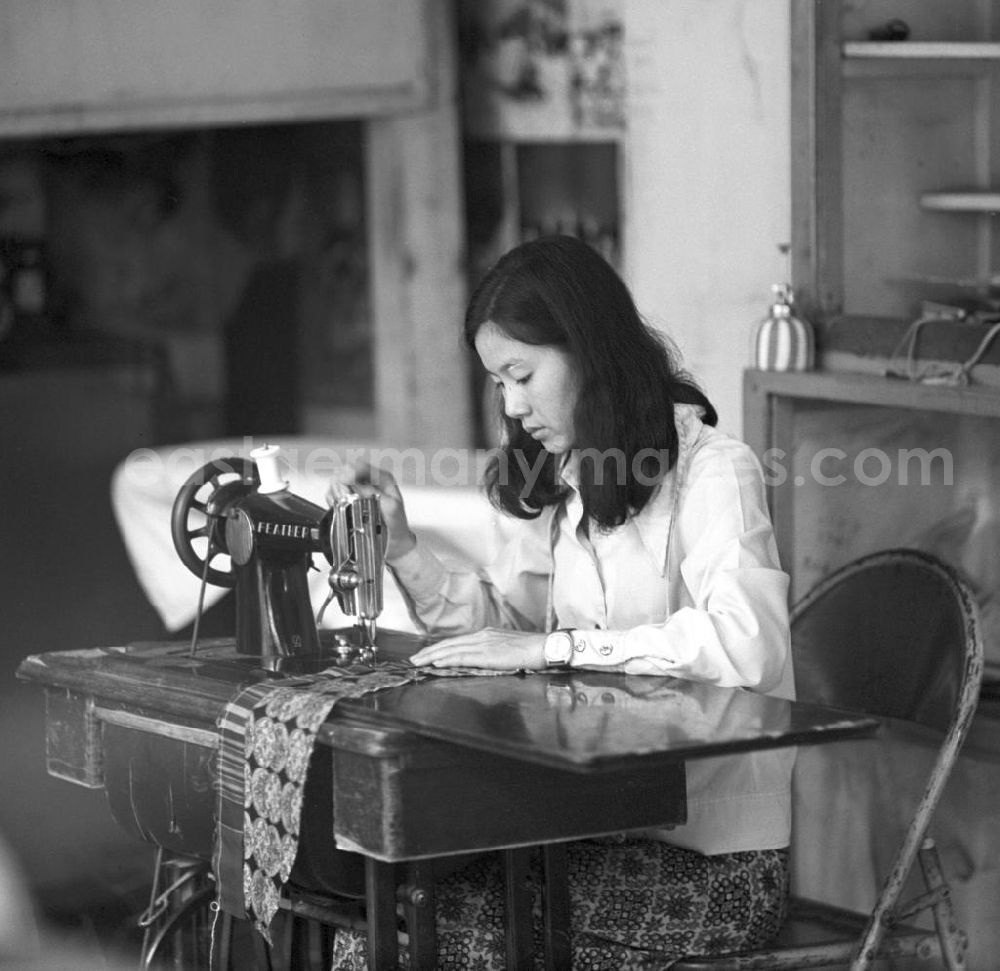 GDR picture archive: Vientiane - Eine Frau näht an einer Nähmaschine der Marke Singer Feather in Vientiane, der Hauptstadt der Demokratischen Volksrepublik Laos.
