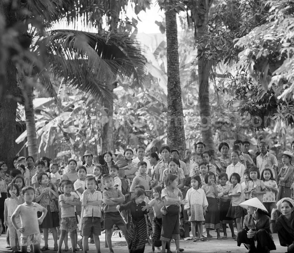 GDR image archive: Vientiane - Ein feierlicher Empfang erwartet die umerzogenen Rückkehrer von der Frauen- und Männerinsel in Vientiane in der Demokratischen Volksrepublik Laos. Das Nam Ngum Reservoir entstand mit der Fertigstellung des gleichnamigen Staudamms im Jahr 1971. Die im See liegenden Inseln dienten in den 7