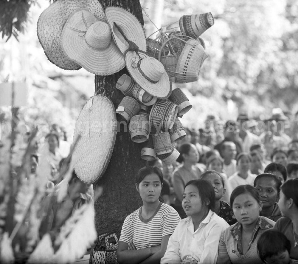 GDR picture archive: Vientiane - Ein feierlicher Empfang erwartet die umerzogenen Rückkehrer von der Frauen- und Männerinsel in Vientiane in der Demokratischen Volksrepublik Laos. Das Nam Ngum Reservoir entstand mit der Fertigstellung des gleichnamigen Staudamms im Jahr 1971. Die im See liegenden Inseln dienten in den 7
