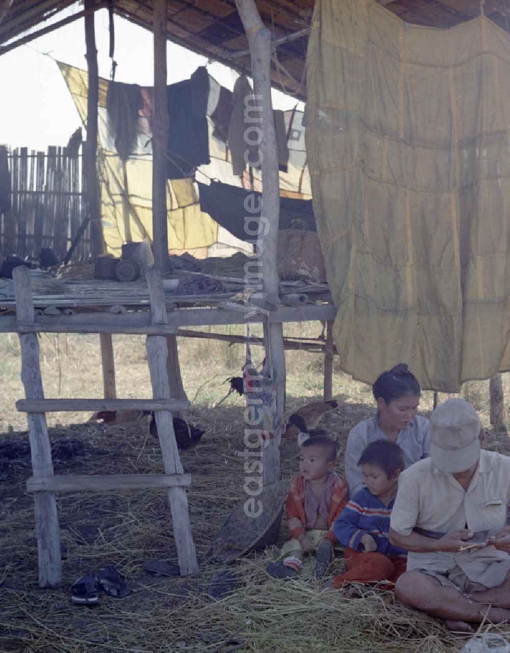 Vientiane: Männer, Frauen und Kinder sitzen während der Reisernte im Schatten einer Hütte auf einem Feld in der Demokratischen Volksrepublik Laos.