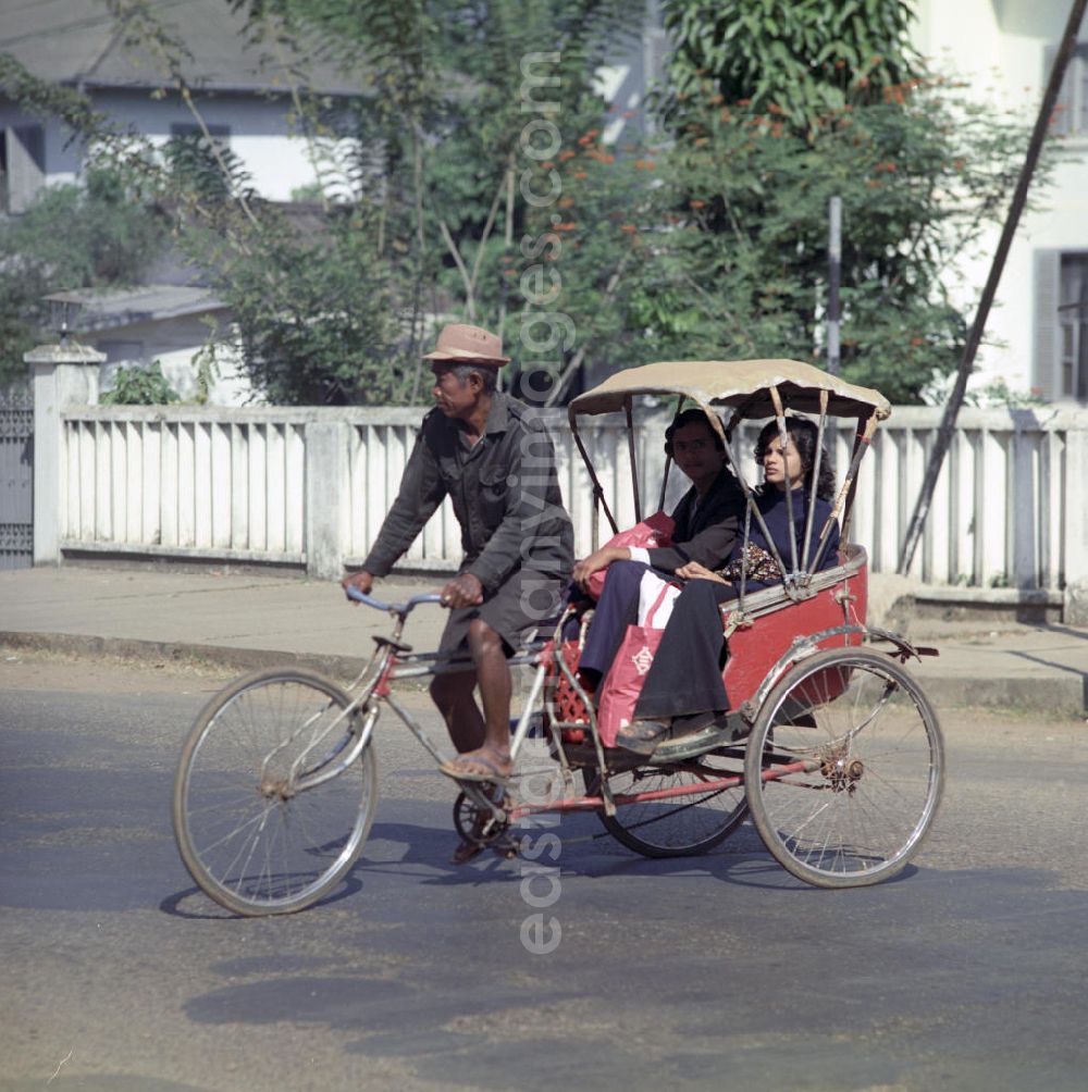GDR picture archive: Vientiane - Ein Paar fährt mit einer Rikscha auf einer Straße in Vientiane, der Hauptstadt der Demokratischen Volksrepublik Laos.