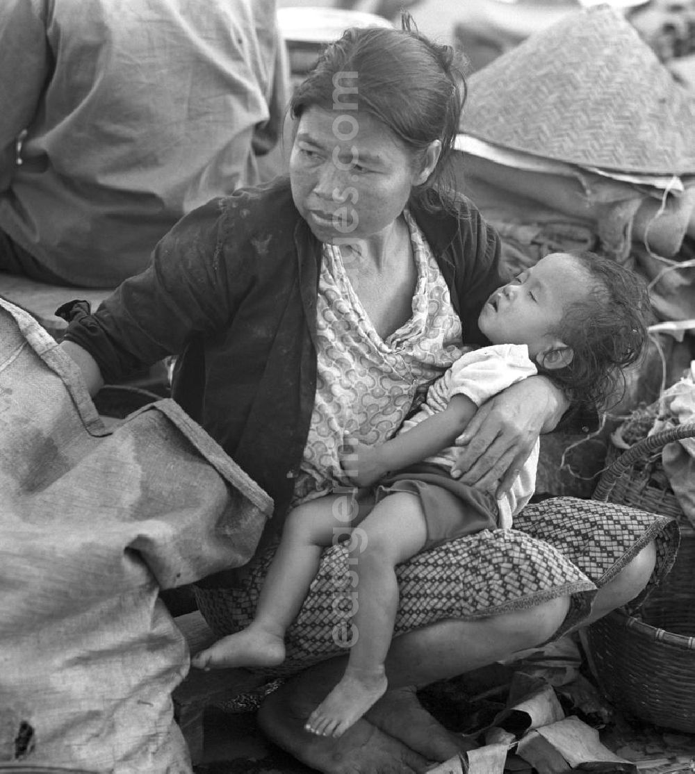GDR photo archive: Vientiane - Ein kleines Kind ist auf dem Arm seiner Mutter eingeschlafen - Marktszene in Vientiane, der Hauptstadt der Demokratischen Volksrepublik Laos.