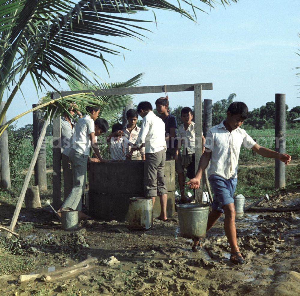 GDR photo archive: Vientiane - Kinder holen Wasser an einem Brunnen, um die Pflanzen in ihrem Schulgarten in einem Dorf in der Demokratischen Volksrepublik Laos zu bewässern.