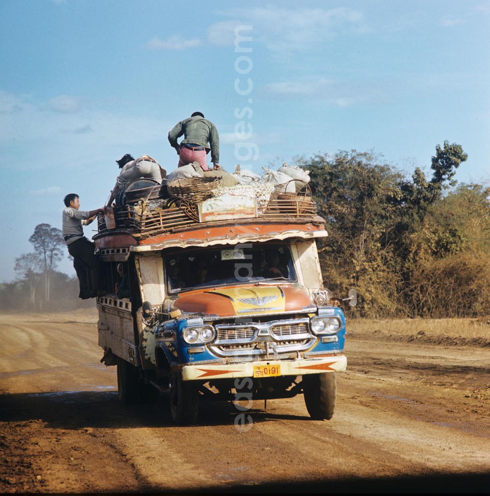 GDR picture archive: Ang Nam Ngum - Mit Waren und Menschen vollbeladener Transporter auf einer Straße in der Demokratischen Volksrepublik Laos.