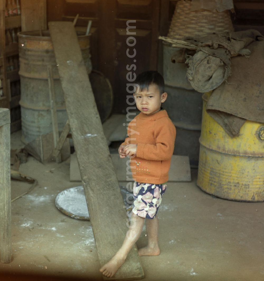 GDR picture archive: Vientiane - Junge vor einer Hütte an einer Straße in der Demokratischen Volksrepublik Laos.