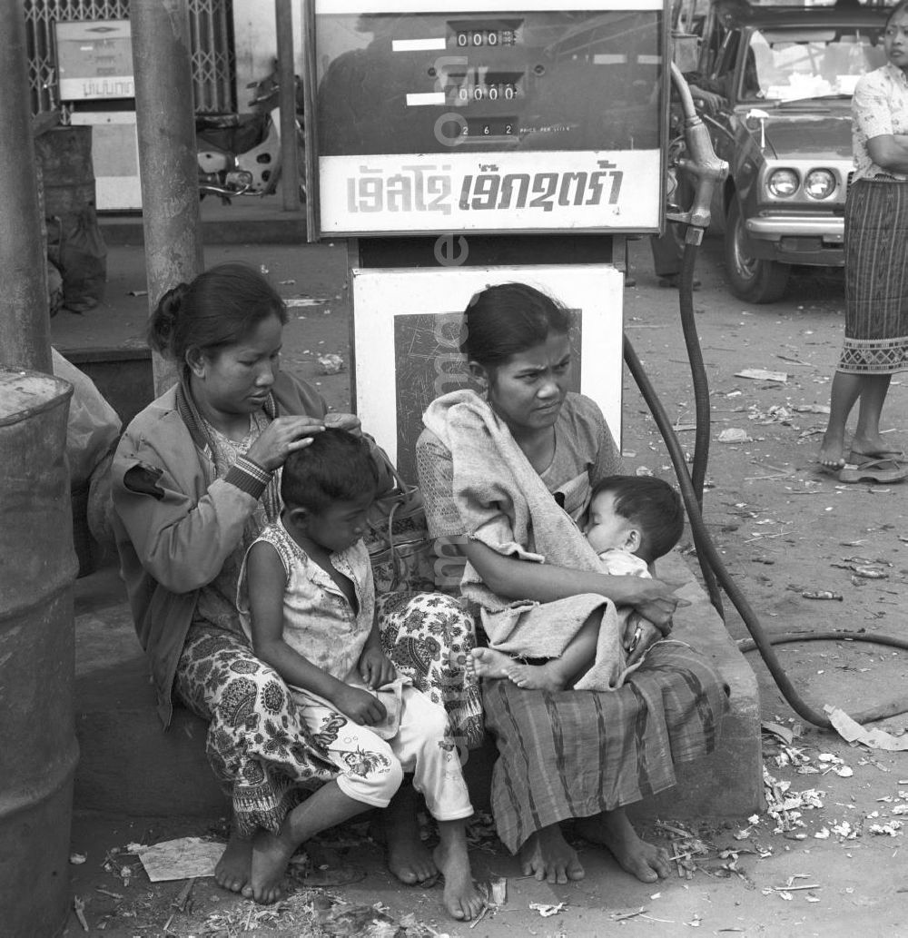 Vientiane: Frauen sitzen mit ihren Kindern vor der Zapfsäule einer Tankstelle in Vientiane in der Demokratischen Volksrepublik Laos.