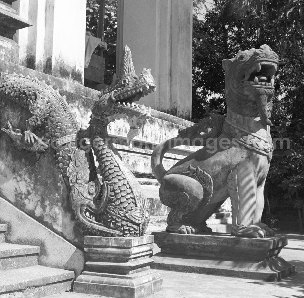 GDR picture archive: Vientiane - Schlange und Löwe aus Stein bewachen den Eingang eines Tempels in Vientiane, der Hauptstadt der Demokratischen Volksrepublik Laos.