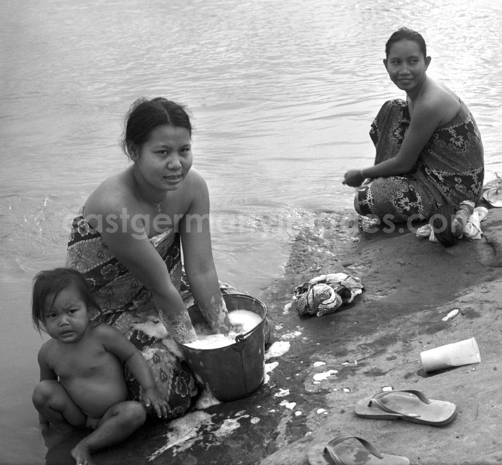 GDR picture archive: Nam Ngum - Frauen baden ihre Kinder und waschen ihre Wäsche im Fluß Mekong in der Demokratischen Volksrepublik Laos.
