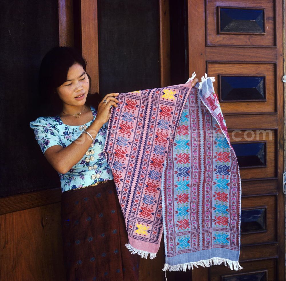 Vientiane: Eine Frau präsentiert zwei Teppiche aus einer Weberei in Vientiane, der Hauptstadt der Demokratischen Volksrepublik Laos.