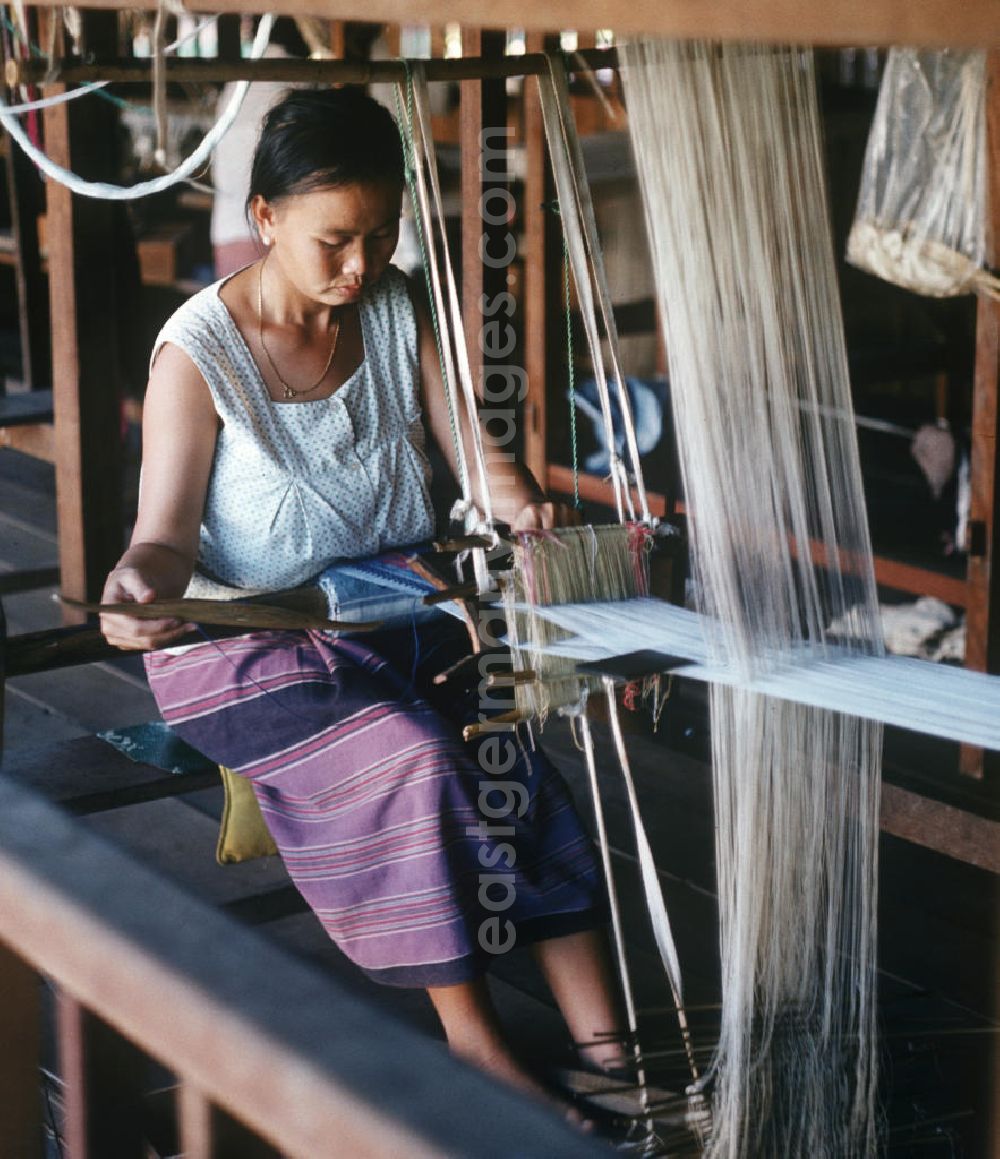 GDR photo archive: Vientiane - Eine Frau webt an einem Holzwebstuhl in einer Weberei in Vientiane, der Hauptstadt der Demokratischen Volksrepublik Laos.