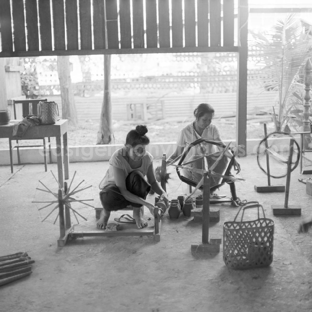 GDR image archive: Vientiane - Frauen bringen Fäden auf die Spulen für die Webstühle in einer Weberei in Vientiane, der Hauptstadt der Demokratischen Volksrepublik Laos.