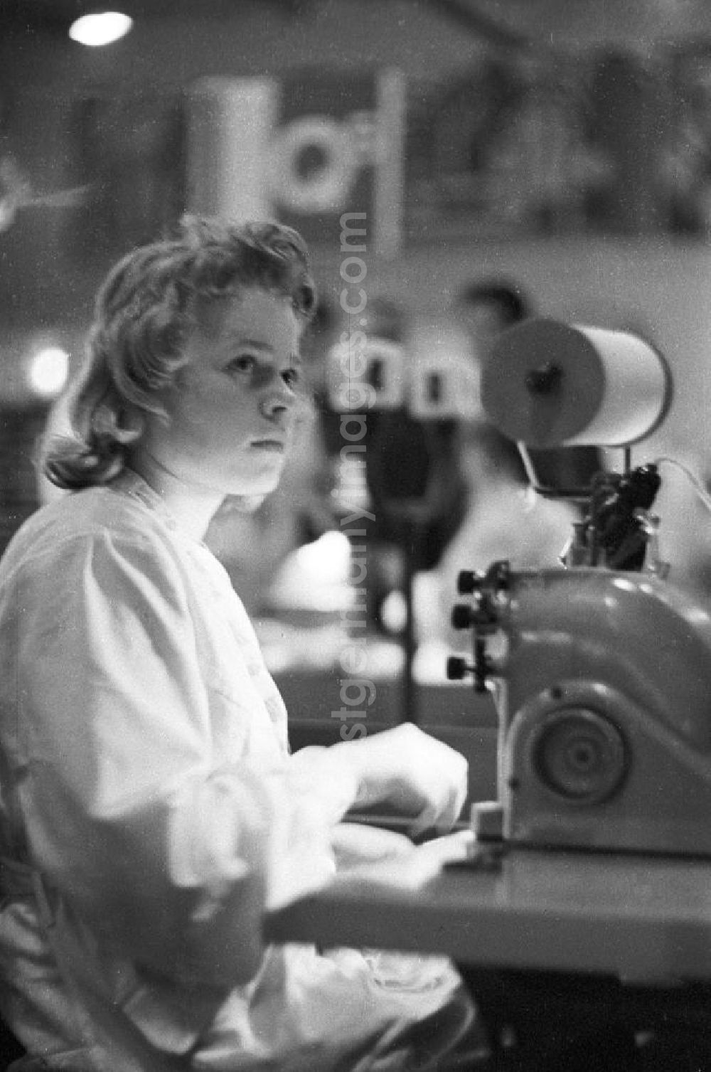 GDR photo archive: Leipzig - Eine Frau präsentiert auf der Lehrschau der Standardisierung eine Nähmaschine. Die Lehrschau der Standardisierung, als zweite Großveranstaltung nach der Konferenz der Standardisierung im Februar 1959, sollte Produktionsverfahren in der Wirtschaft verbessern. Bestmögliche Qualität nach Vorlage!