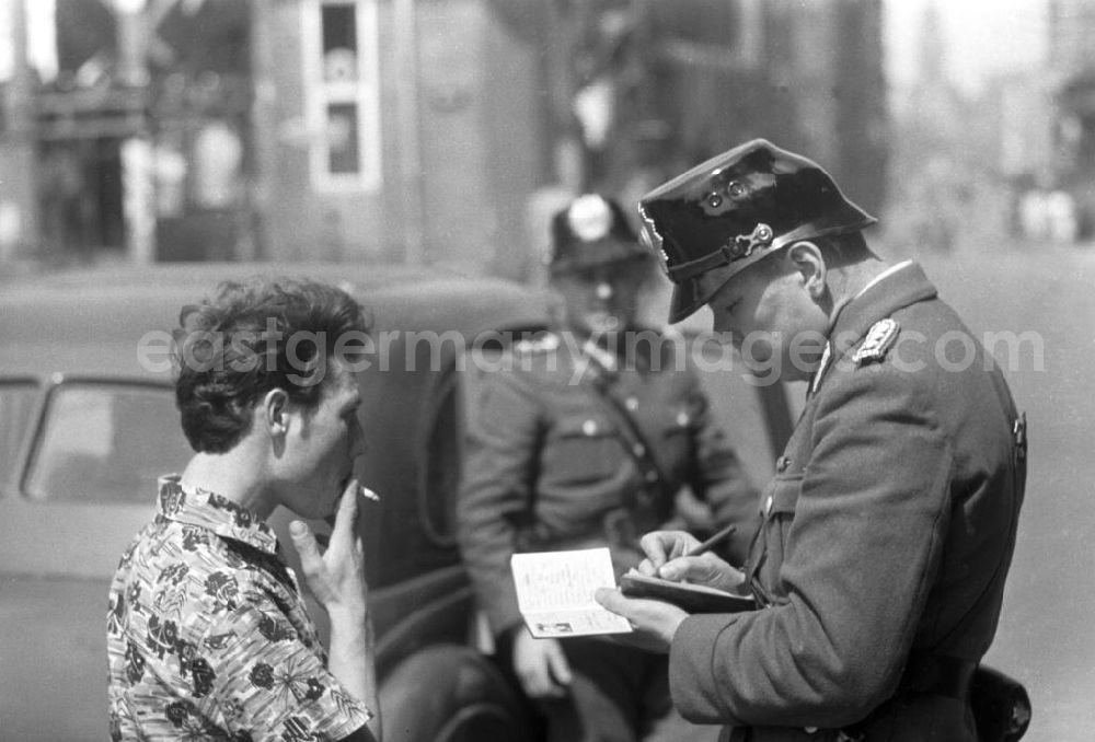 GDR picture archive: Leipzig - Ein Volkspolizist kontrolliert einen Passanten und notiert sich die Angaben aus dessen Personalausweis.