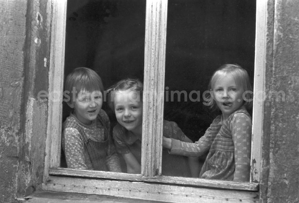 GDR photo archive: Leipzig - Drei Mädchen schauen neugierig aus dem Fenster eines Altbaus in Leipzig.