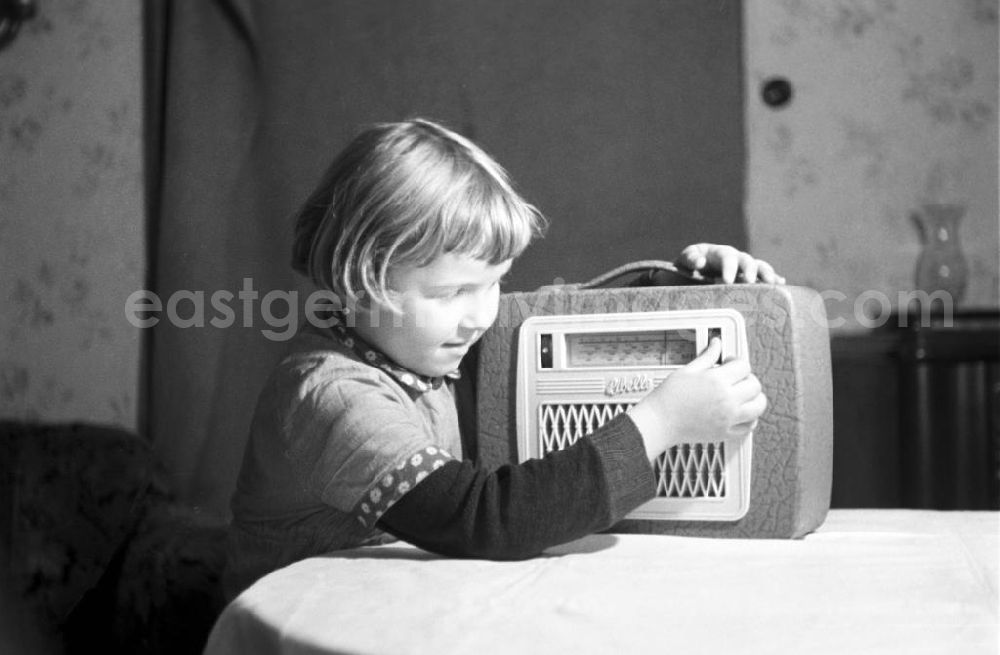 GDR image archive: Leipzig - Ein Mädchen spielt am Kofferradio Libelle in einer Wohnung. Das Kofferradio Libelle vom VEB Funkwerk Halle war eines der ersten Kofferradios der DDR.