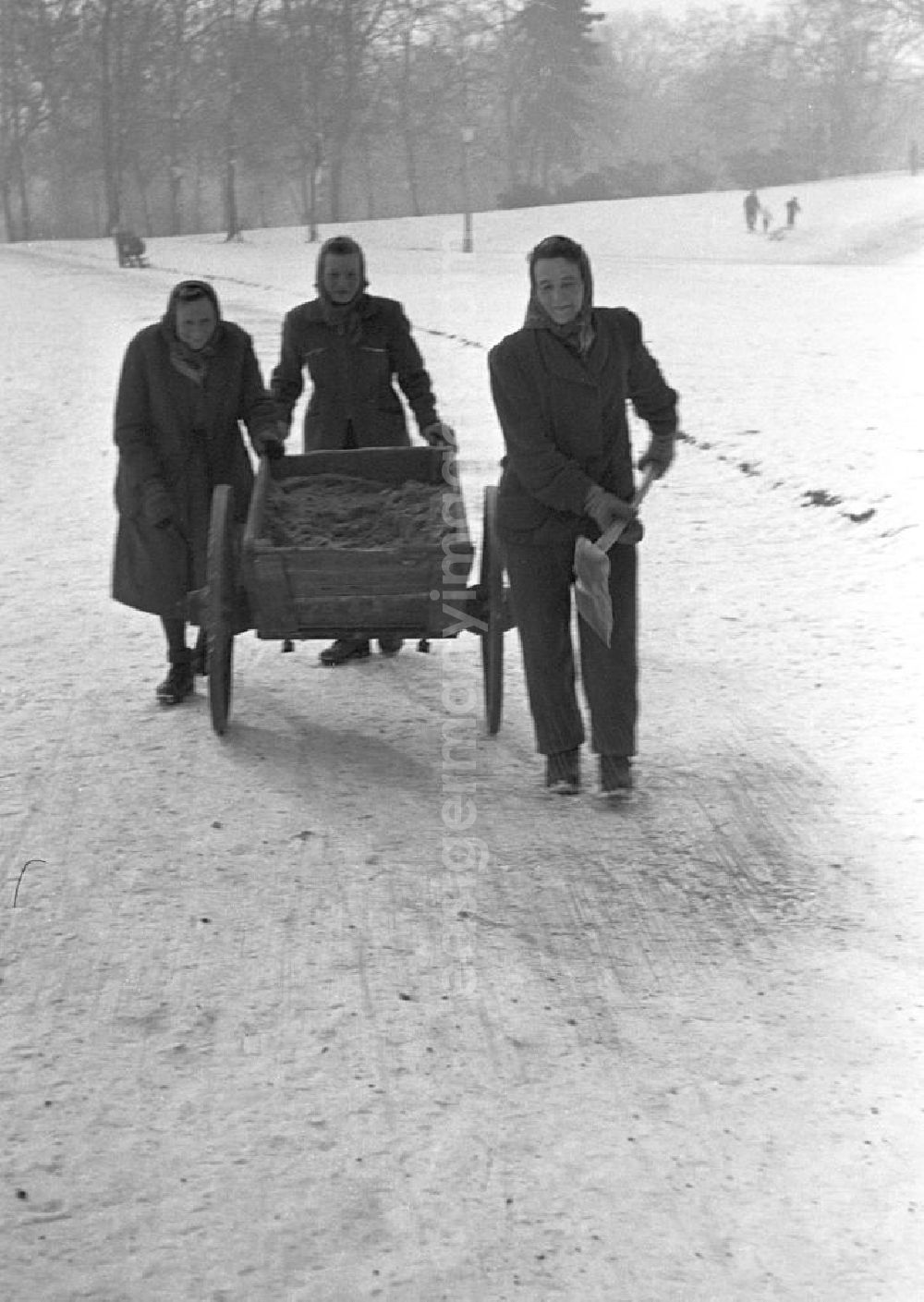 GDR image archive: Leipzig - Frauen streuen im Winter mit Karren und Schippe Sand auf die vereisten Fußwege im Clara-Zetkin-Park in Leipzig.