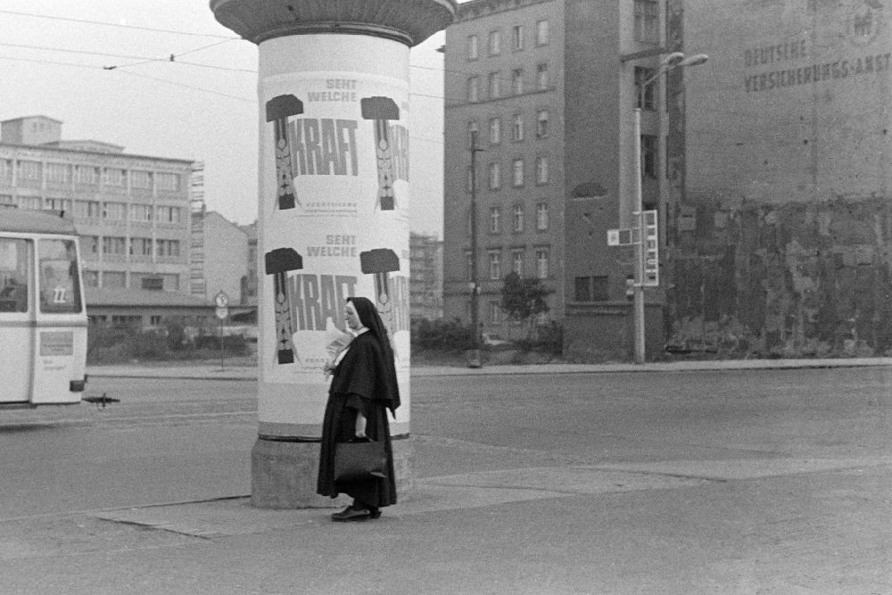Leipzig: Advertisement with advertising See what power with a nun walking past an advertising column on a sidewalk on Augustusplatz in the Mitte district in Leipzig, Saxony in the territory of the former GDR, German Democratic Republic