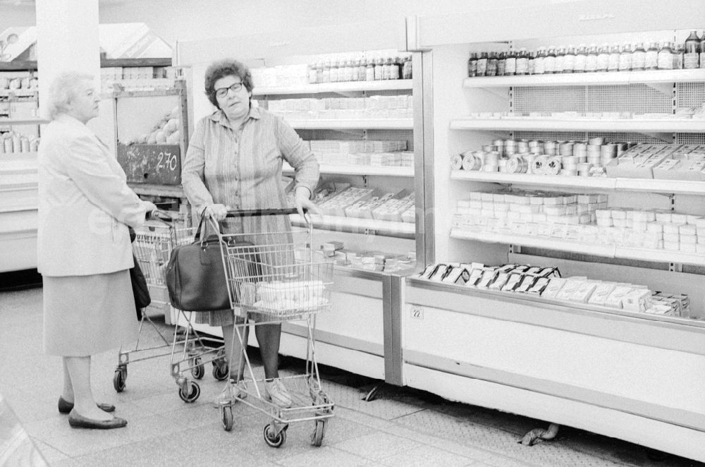 GDR image archive: Berlin - 2 elderly ladies chatting in front of the refrigerated shelves in a department store in Berlin, the former capital of the GDR, the German Democratic Republic. The shelves are filled partly with Ostprodukten as well with Western products