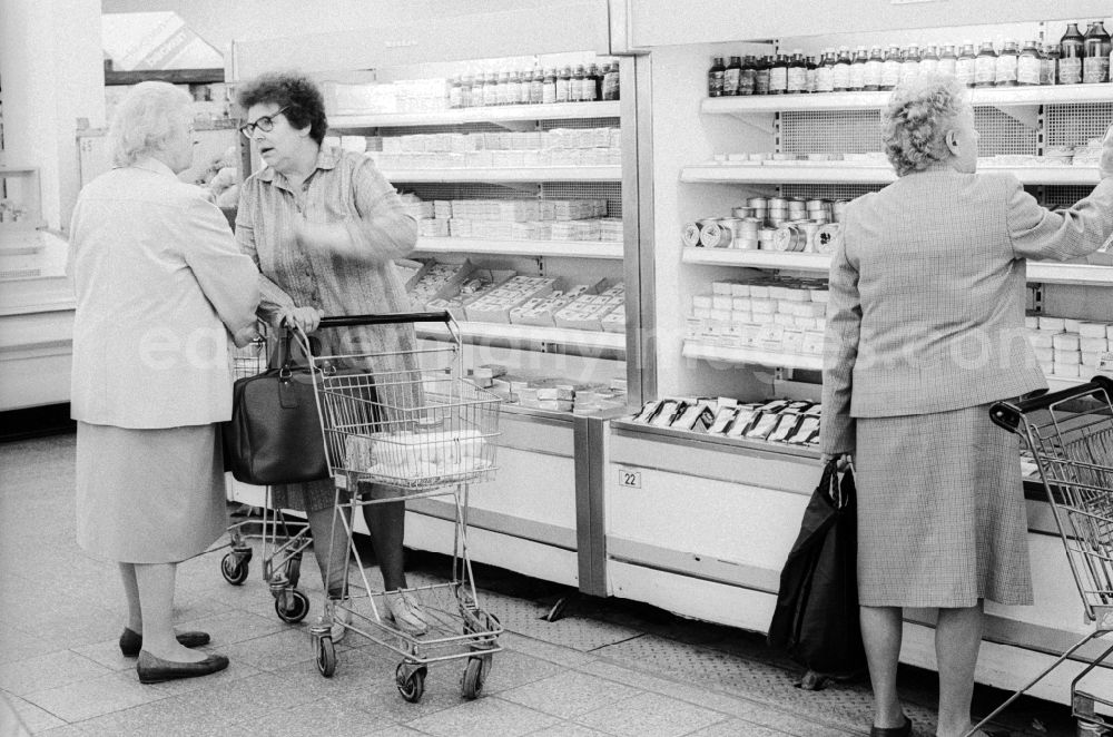 GDR photo archive: Berlin - 2 elderly ladies chatting in front of the refrigerated shelves in a department store in Berlin, the former capital of the GDR, the German Democratic Republic. The shelves are filled partly with Ostprodukten as well with Western products