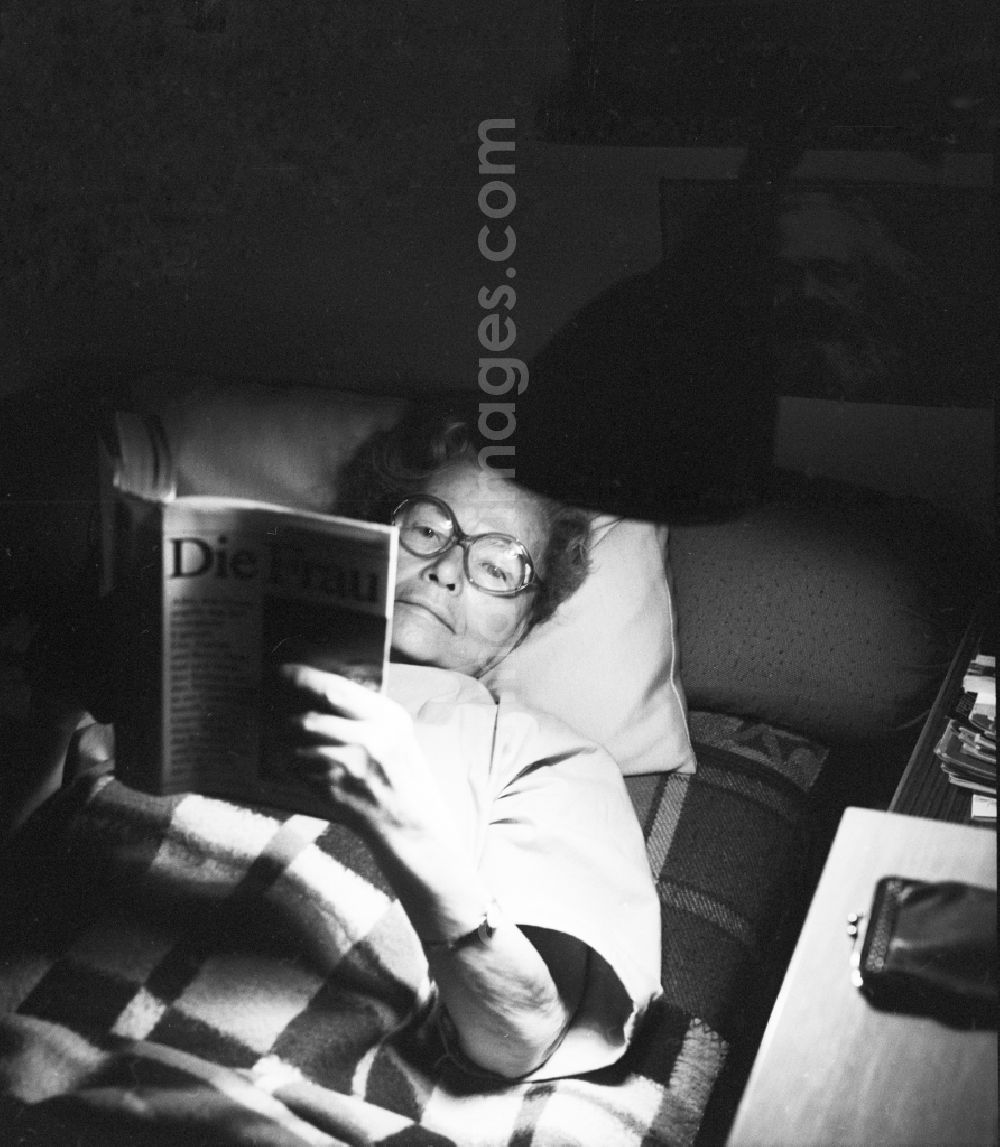 GDR picture archive: Berlin - Elderly woman reading a book while lying in Berlin