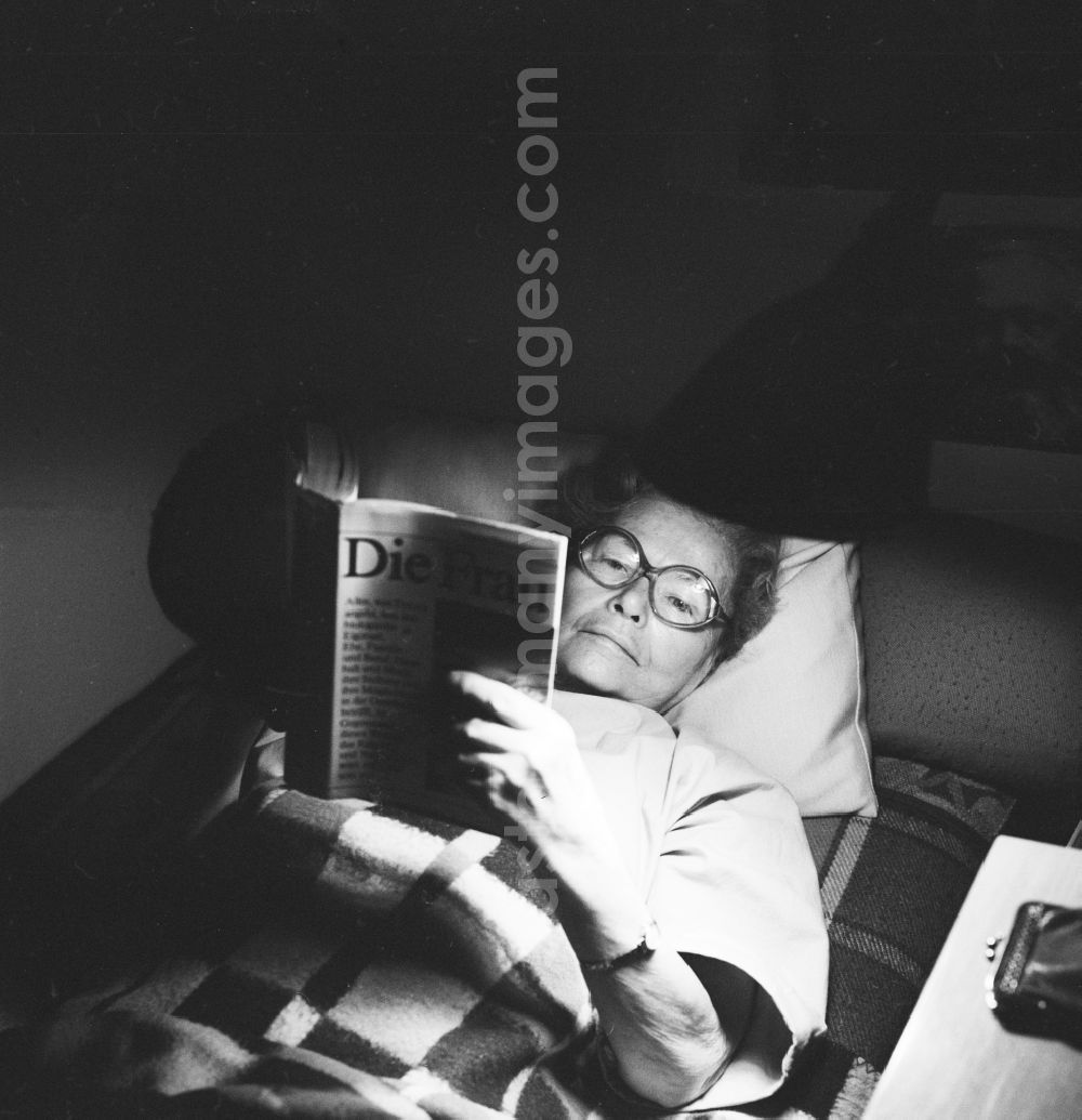 Berlin: Elderly woman reading a book while lying in Berlin