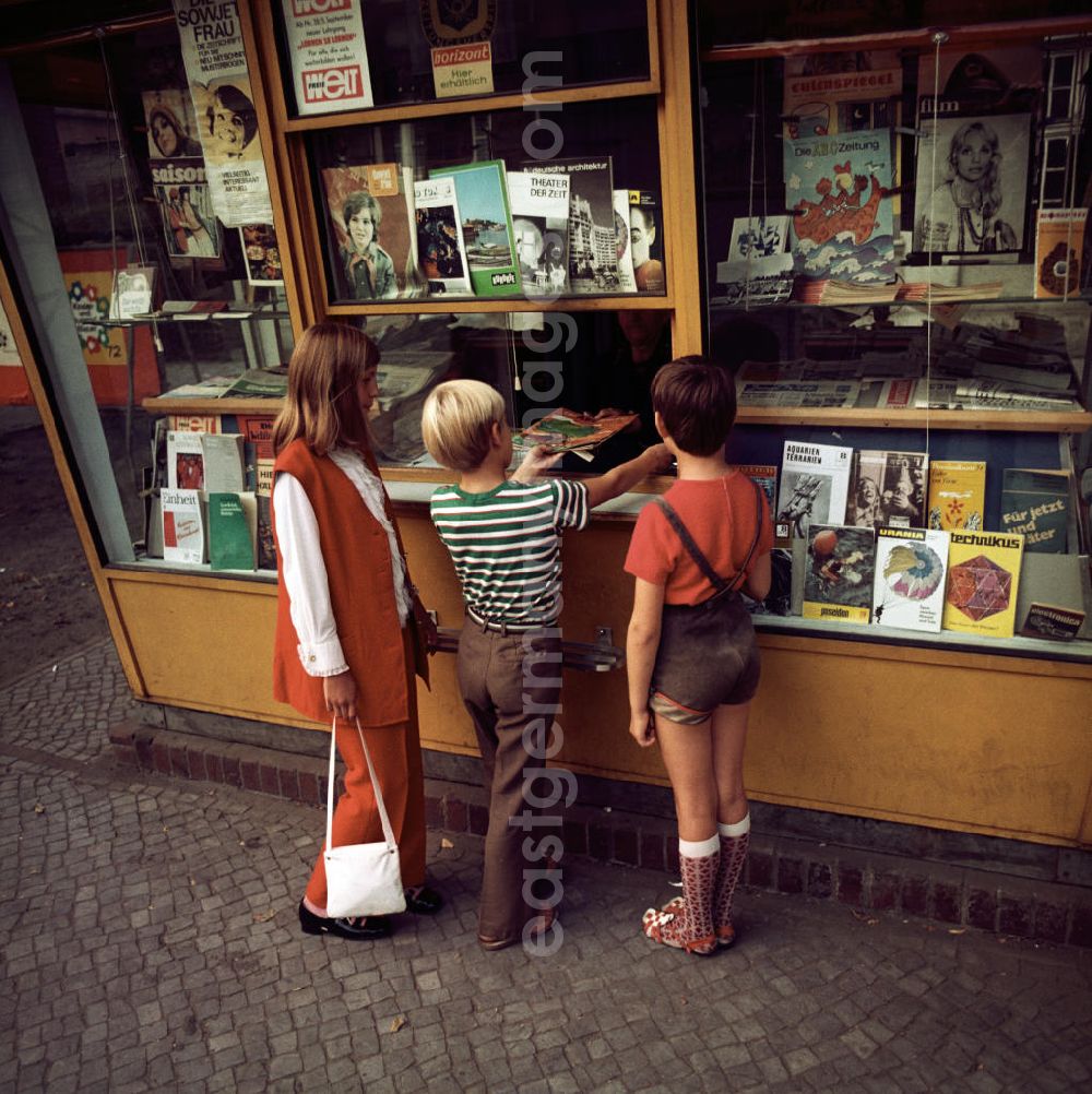 GDR photo archive: Potsdam - Kinder kaufen ein Magazin an einem Zeitungskiosk in Potsdam. In der Auslage verschiedene Zeitschriften, Magazine und Illustrierte.