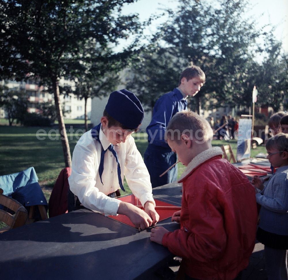 GDR picture archive: Berlin - Pioneers and members of the Free German Youth tinker dragon with children at a craft street in the street Schillingstrasse in Berlin-Mitte on May Day