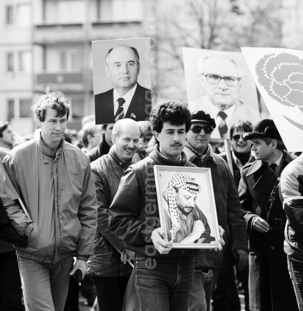 Berlin: Enthusiastic GDR citizens at the May 1 demonstration in Berlin, the former capital of the GDR, German Democratic Republic. A guest worker wears a portrait of Yasser Arafat