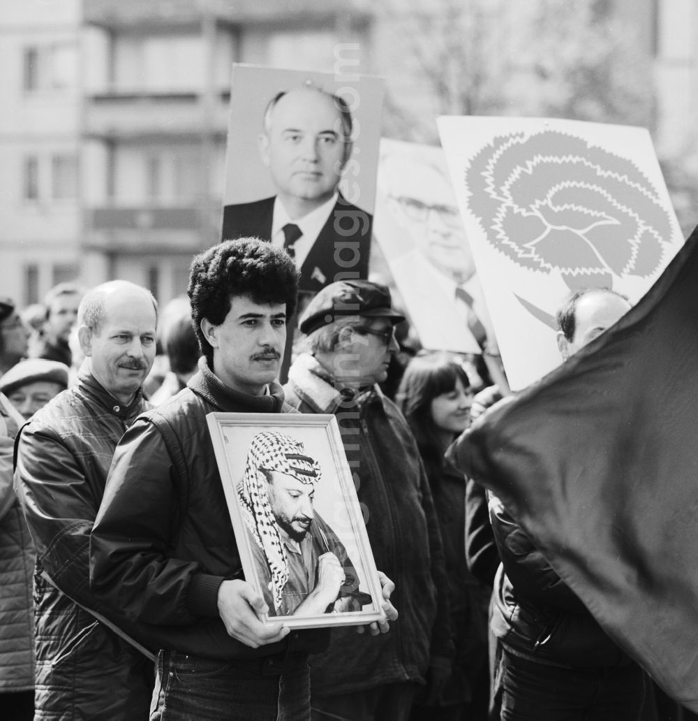 GDR image archive: Berlin - Enthusiastic GDR citizens at the May 1 demonstration in Berlin, the former capital of the GDR, German Democratic Republic. A guest worker wears a portrait of Yasser Arafat