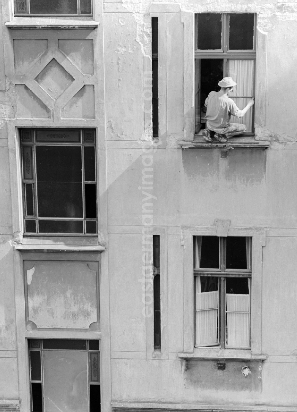 GDR picture archive: Berlin - A painter sweeps window in a backyard in Berlin, the former capital of the GDR, the German Democratic Republic