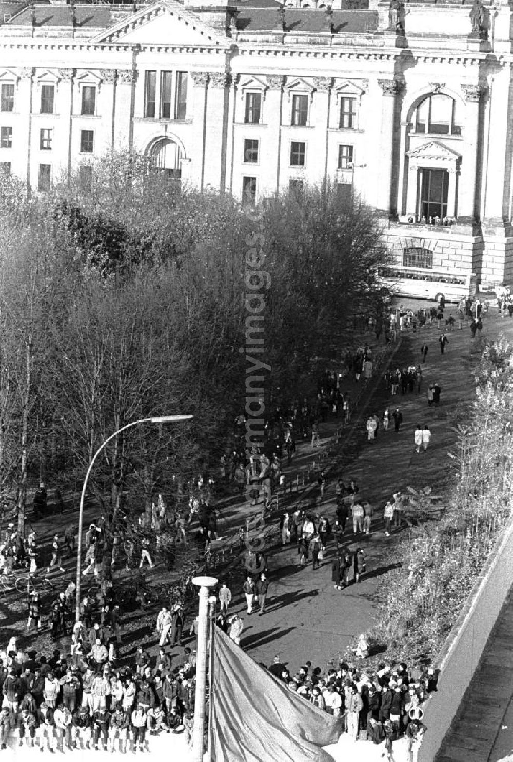 GDR image archive: Berlin - Blick vom Brandenburger Tor auf Menschen welche auf der Mauer sitzen bzw. stehen. Im Hintergrund der Reichstag.
