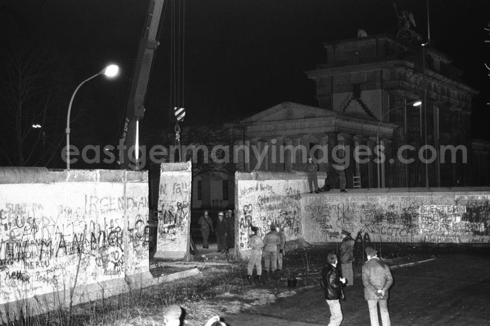 Berlin- Mitte: Nachtaufnahme: Maueröffnung / Mauerabbau am Brandenburger Tor. Kran hebt Mauerstück / Mauersegment.