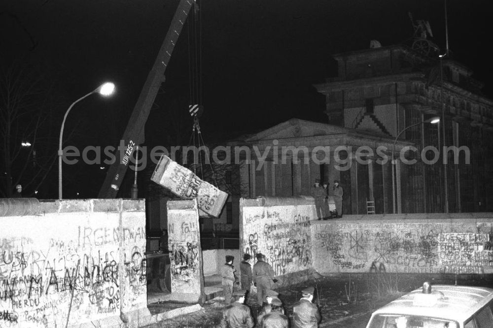 GDR picture archive: Berlin- Mitte - Nachtaufnahme: Maueröffnung / Mauerabbau am Brandenburger Tor. Kran hebt Mauerstück / Mauersegment.