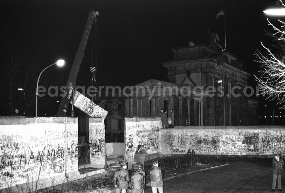 Berlin- Mitte: Nachtaufnahme: Maueröffnung / Mauerabbau am Brandenburger Tor. Kran hebt Mauerstück / Mauersegment.