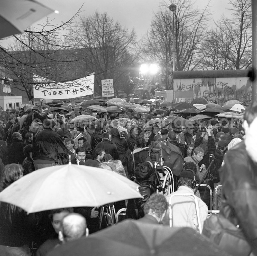 GDR image archive: Berlin - Happening around the Brandenburg Gate during the wall opening at the Berlin Wall fell in November 1989 in Berlin. View over Members of the press on crowds which pass through an open section of wall at the Brandenburg Gate