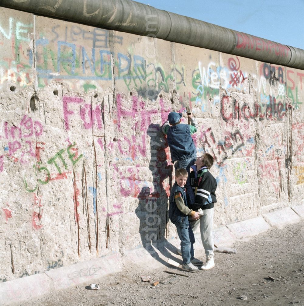 GDR picture archive: Berlin - Wallpeckers and souvenir collectors at the Berlin Wall in Berlin. As wallpeckers people were popularly known, the edited the Berlin Wall after the Wall fell in 1989 and crushed