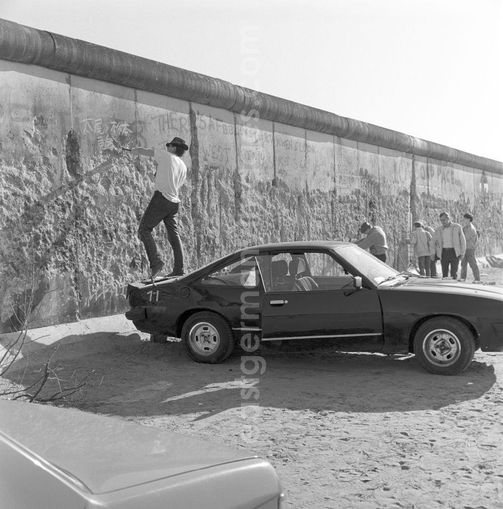 GDR image archive: Berlin - Wallpeckers and souvenir collectors at the Berlin Wall in Berlin. As wallpeckers people were popularly known, the edited the Berlin Wall after the Wall fell in 1989 and crushed