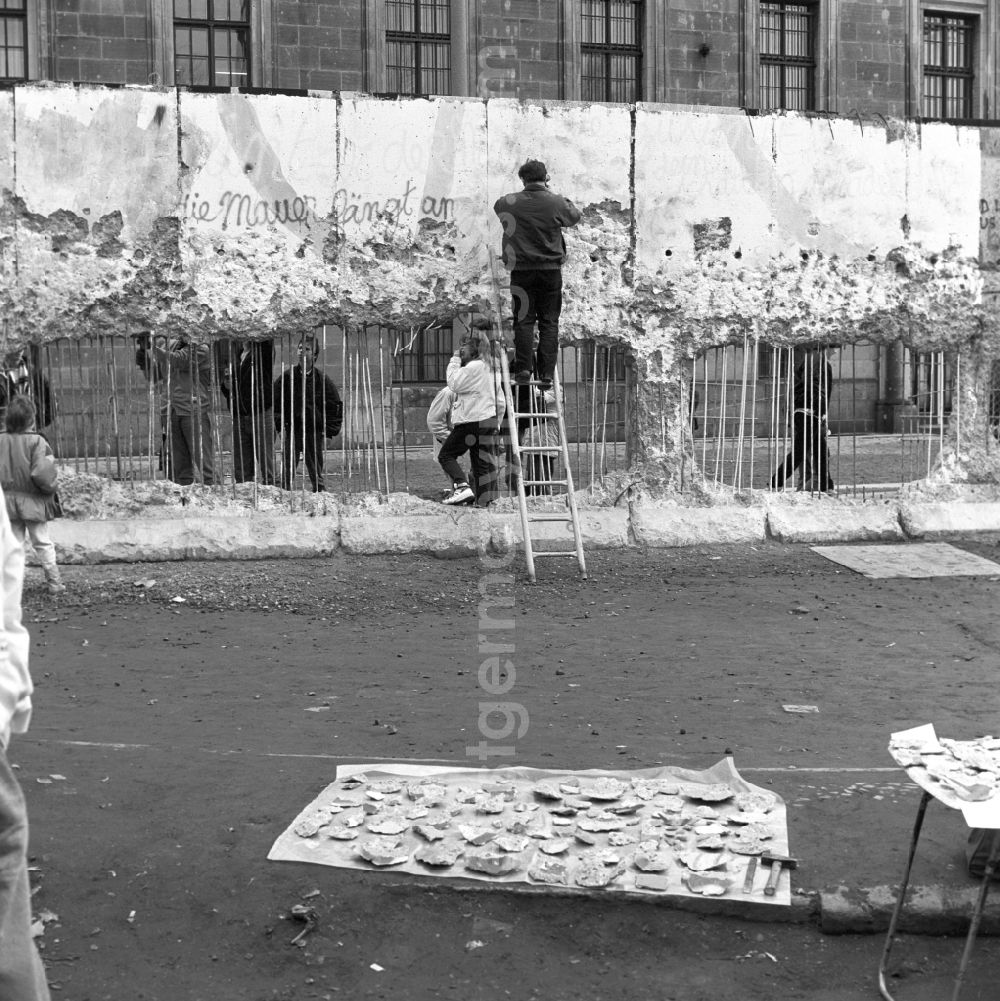 GDR picture archive: Berlin - Wallpeckers and souvenir collectors at the Berlin Wall in Berlin. As wallpeckers people were popularly known, the edited the Berlin Wall after the Wall fell in 1989 and crushed