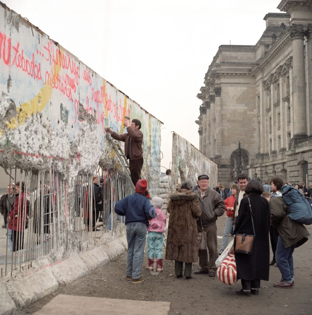 GDR photo archive: Berlin - Wallpeckers and souvenir collectors at the Berlin Wall at the Reichstag building in Berlin. As wallpeckers people were popularly known, the edited the Berlin Wall after the Wall fell in 1989 and crushed