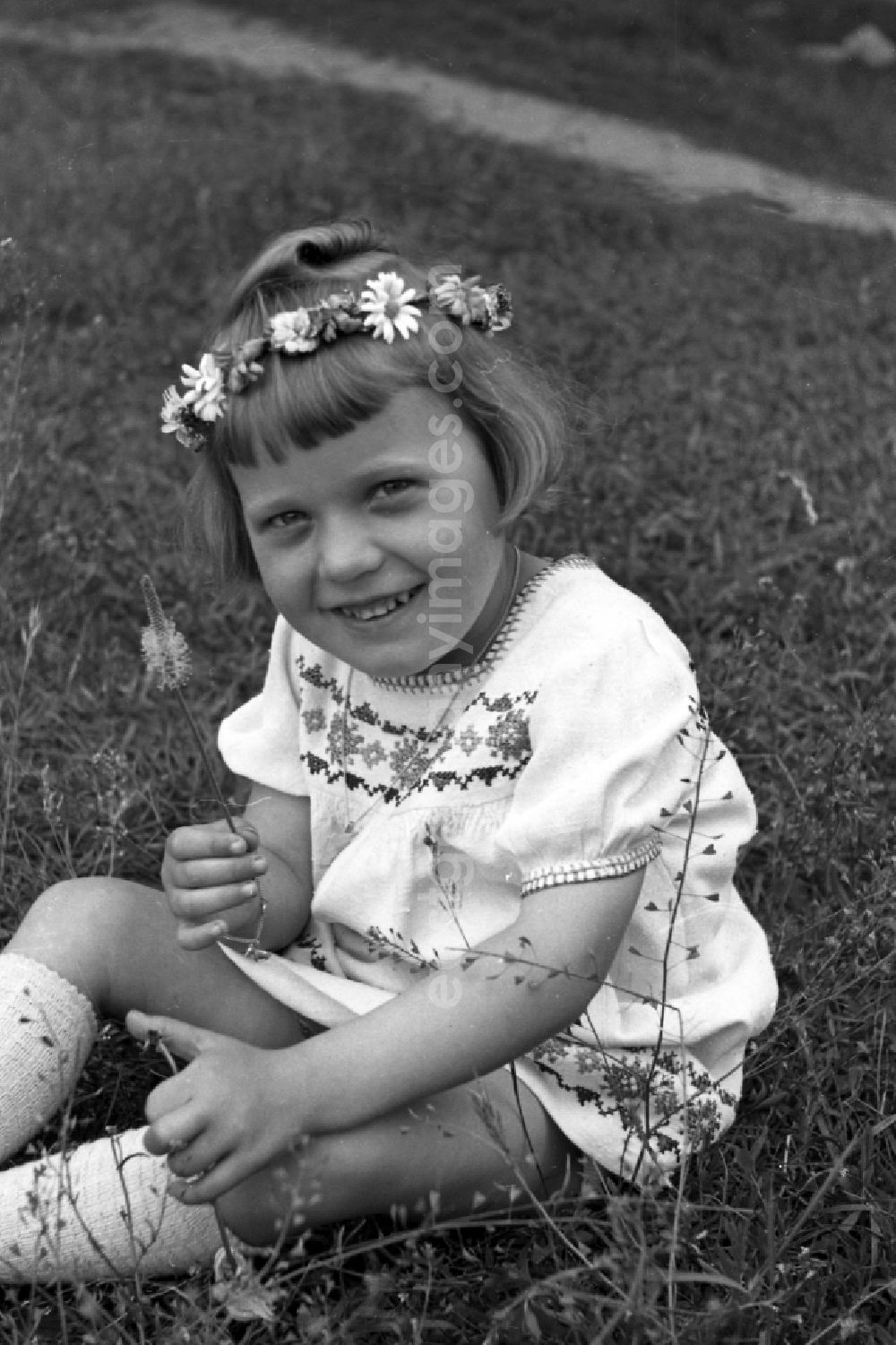 GDR image archive: Bansin - A small girl with floral wreath sits on a meadow in Bansin in the federal state Mecklenburg-West Pomerania in the area of the former GDR, German democratic republic