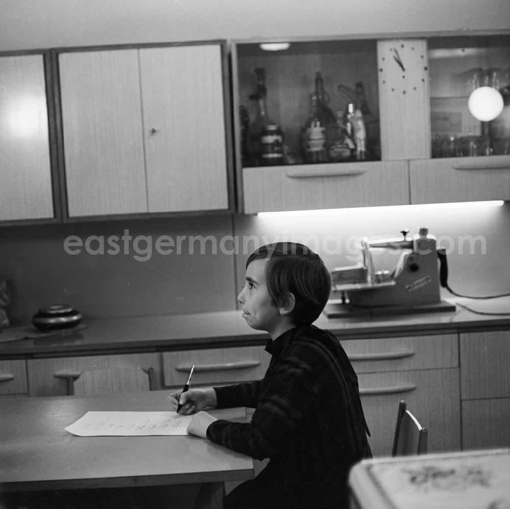 GDR photo archive: Berlin - Friedrichshain - A girl sitting in the kitchen and writes in Berlin - Friedrichshain