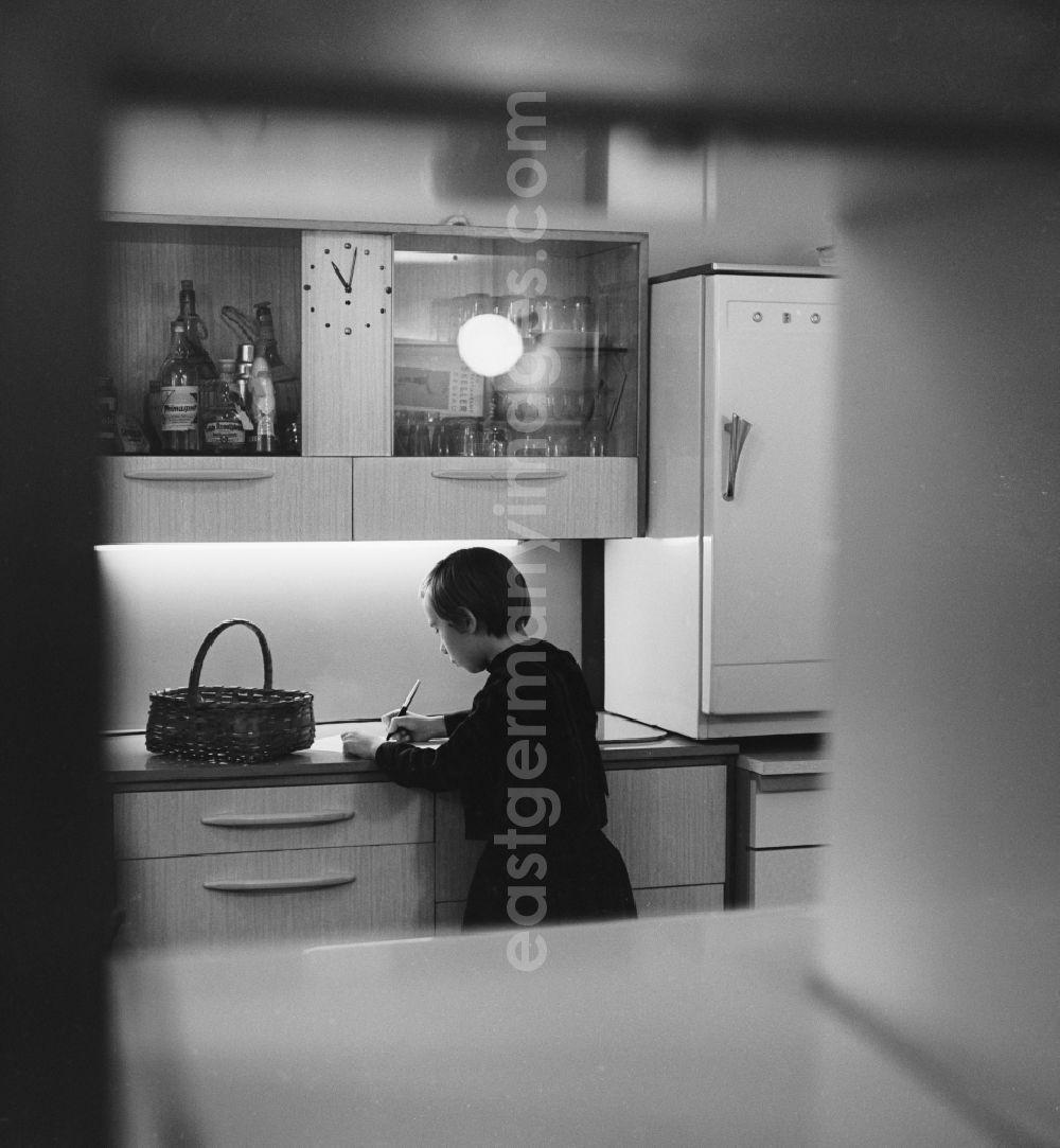 GDR picture archive: Berlin - Friedrichshain - A girl standing in the kitchen and writes in Berlin - Friedrichshain