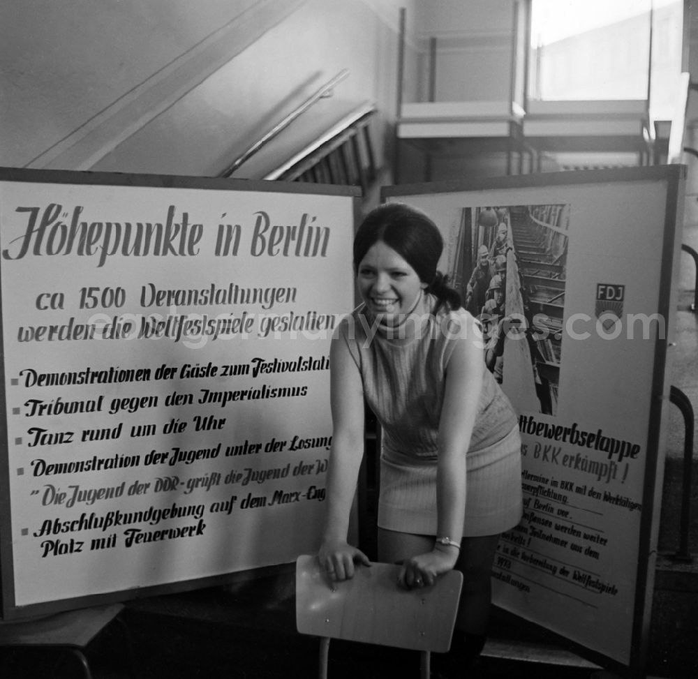 GDR photo archive: Lauchhammer - A girl stands in front of a billboard that focuses on the 1973 World Festival, with the inscription Highlights in Berlin in Lauchhammer in the federal state of Brandenburg on the territory of the former GDR, German Democratic Republic