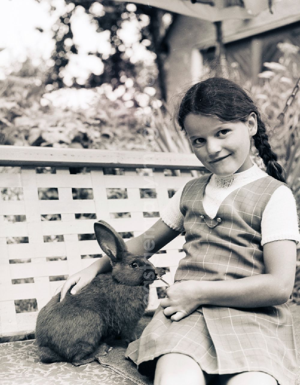 GDR photo archive: Scheibenberg - Girl sits with a rabbit of a garden swing in Scheibenberg in the federal state Saxony in the area of the former GDR, German democratic republic