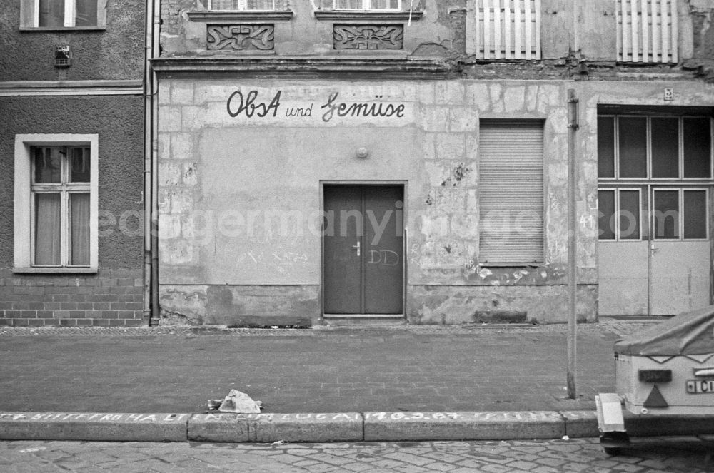 GDR image archive: Berlin - Street view of an apartment building - building front with a bricked-up shop for fruit and vegetables on street Schreinerstrasse in Berlin Eastberlin on the territory of the former GDR, German Democratic Republic