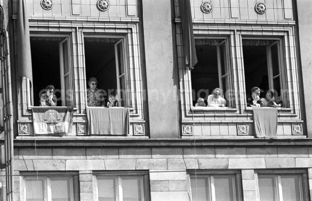 GDR image archive: Magdeburg - People look out the window of her apartment in Magdeburg. The facade of residential house was decorated with flags on the occasion of May 1st